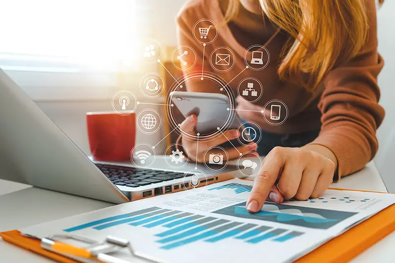 Woman working in front of her laptop while holding her mobile phone