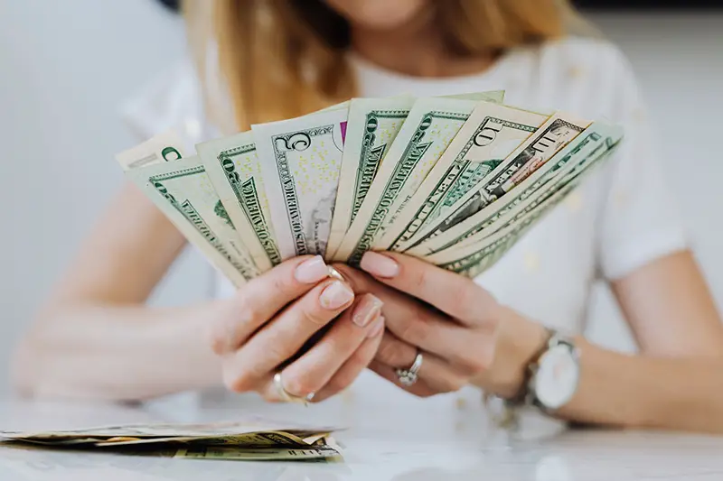 Woman holding fan of dollar bills