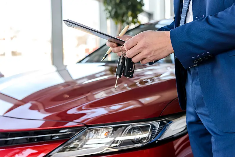 Red car and car agent holding keys