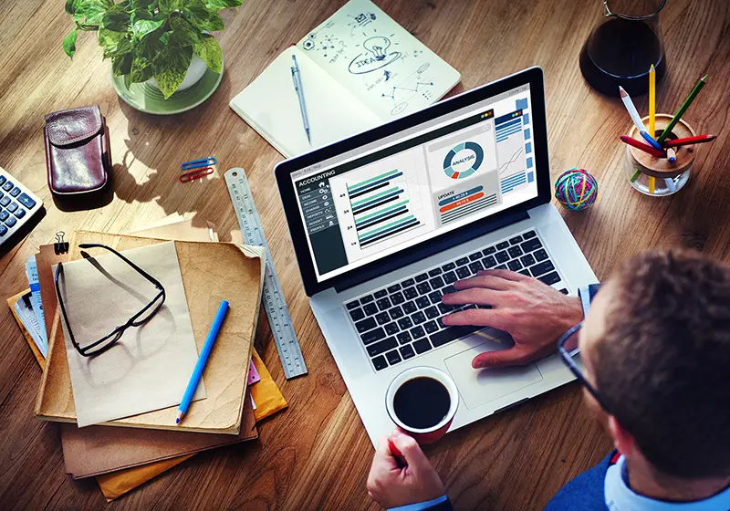 Man holding cup of coffee while working in front of his laptop