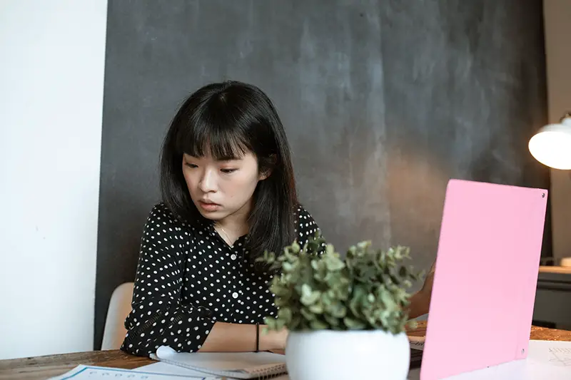 girl in black and white polka dot long sleev shirt sitting at desk working