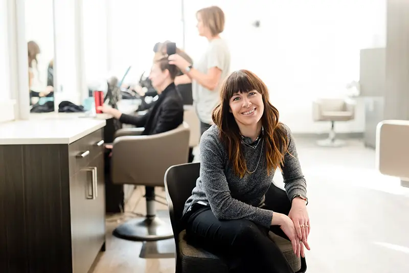 Woman wearing gray long sleeve sitting in a black chair