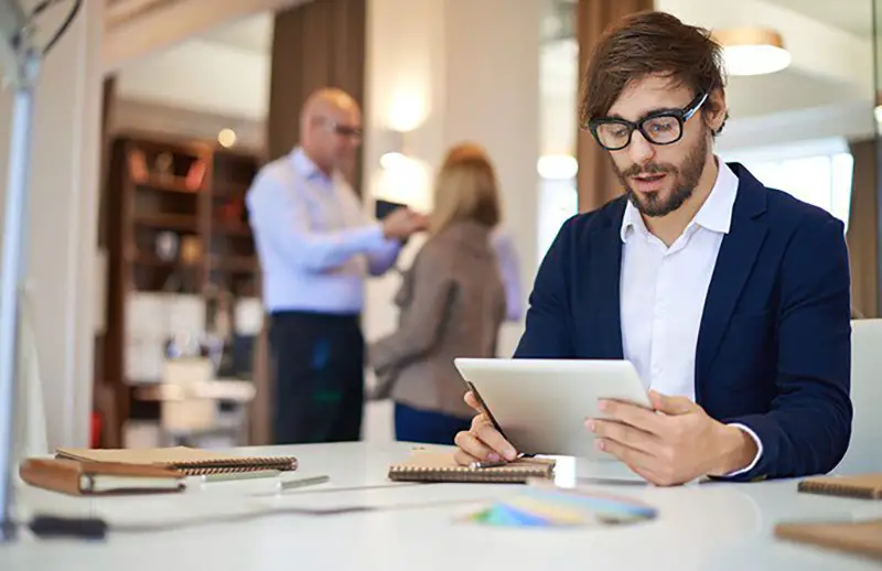 Man wearing eyeglasses holding his silver iPad