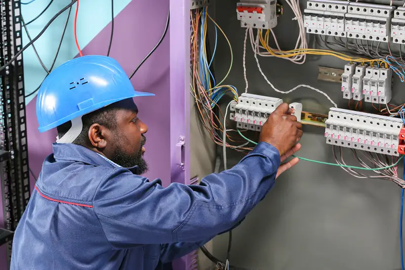 African-American electrician performing wiring in distribution board