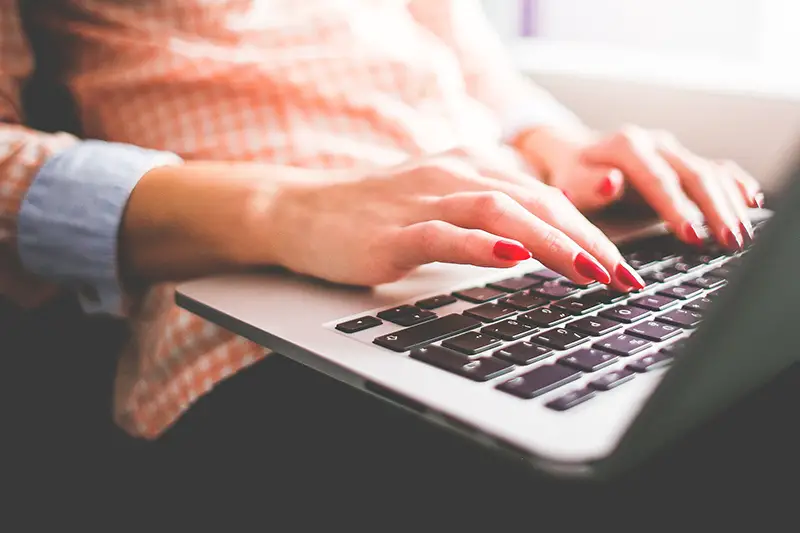 Woman with red nail polished typing on her laptop