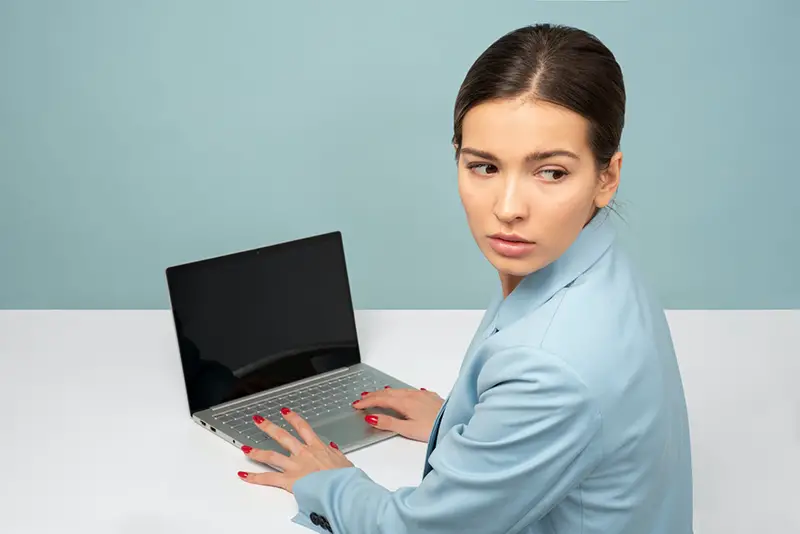 woman using laptop and looking over her shoulder – cybersecurity concept
