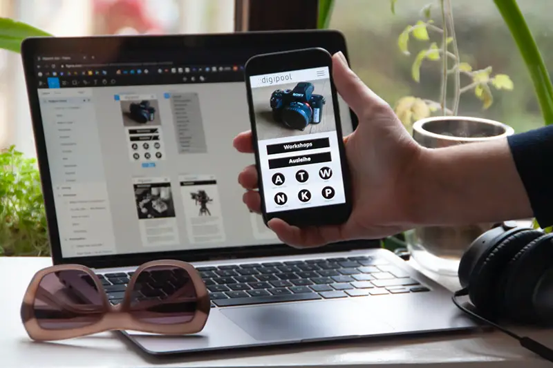 Person holding black smartphone near his laptop