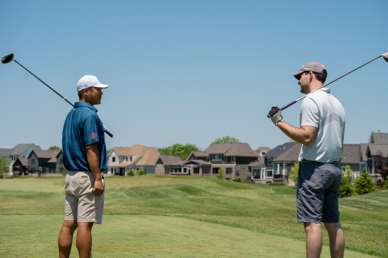 Two men in shorts and t-shirts on the golf course- playing golf