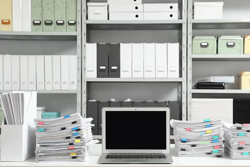 Laptop and documents on desk in office. Space for text