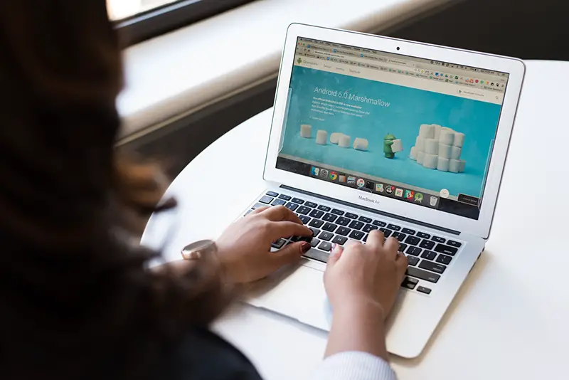 Woman sitting near table using macbook