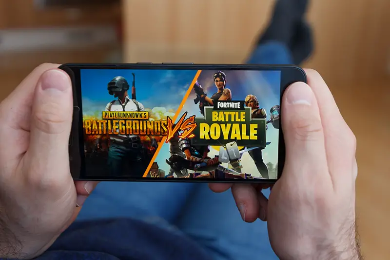 Lying Man holding a smartphone and compares PUBG and Battle Royale games on the smartphone screen.