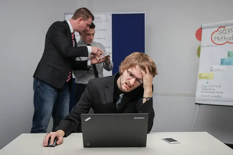 Man sitting on chair in front of his laptop while hands on his head