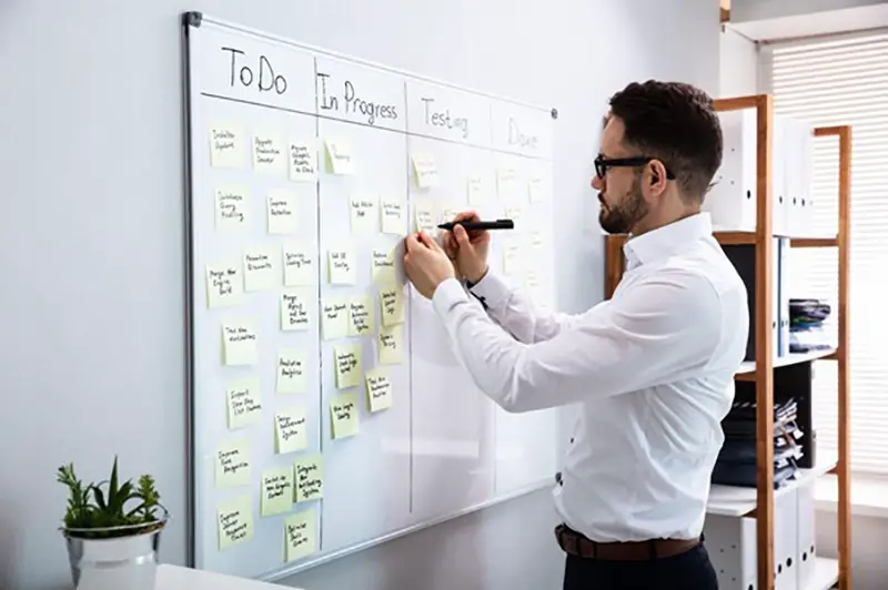 Person holding pen writing on white board