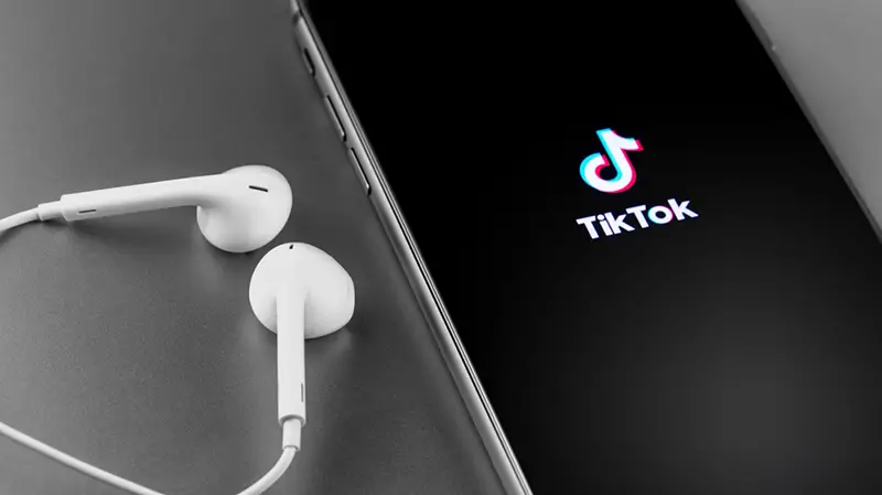 TikTok logo on the screen iPhone with Earpods. TikTok is app to create and share videos