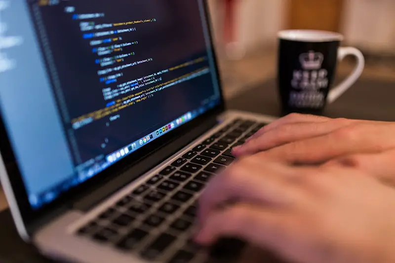 Person typing code in his computer