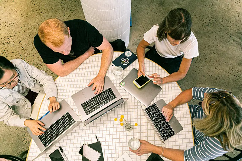 Four people using laptop and smartphone