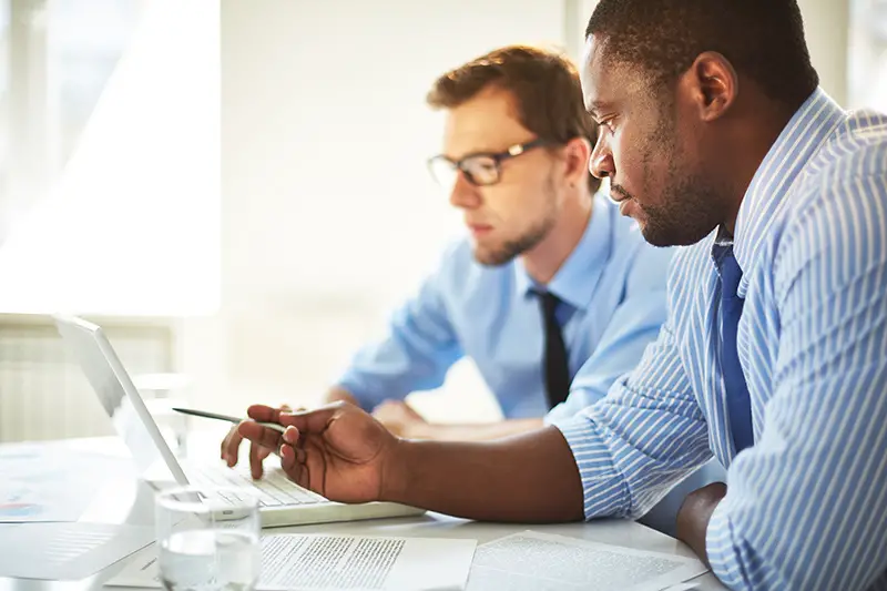 Man pointing at laptop for his colleague