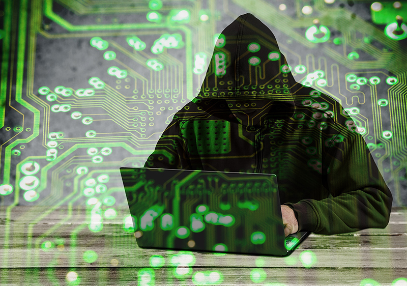 Hacker wearing black hoodie using laptop