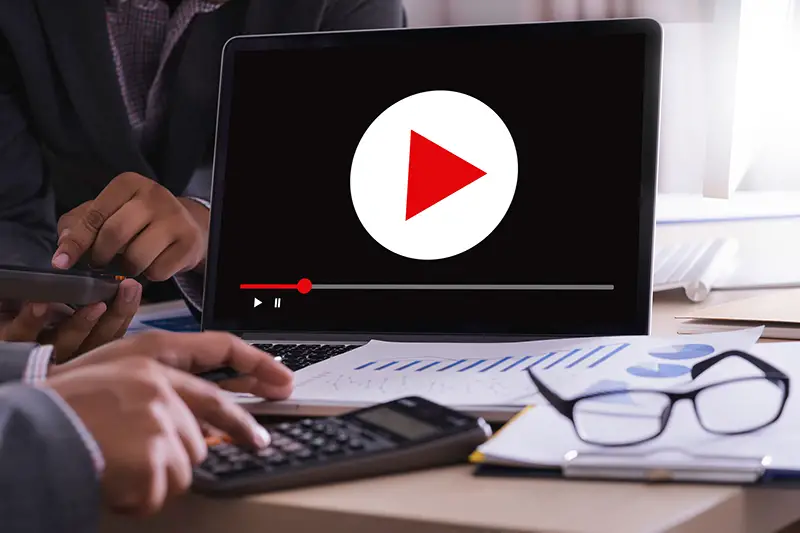 two people talking with laptop on the table appearing a play button on the screen