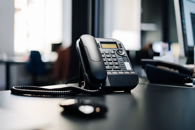 Black IP phone on black desk