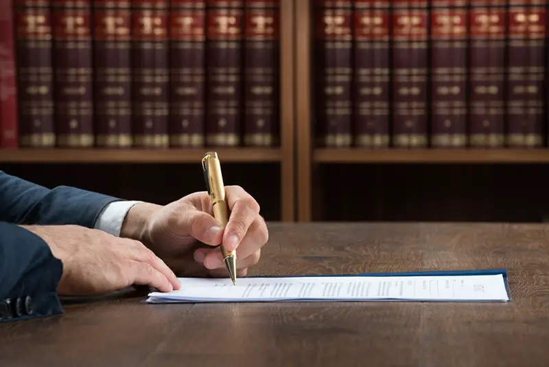 Cropped image of male lawyer writing on legal documents at desk in courtroom