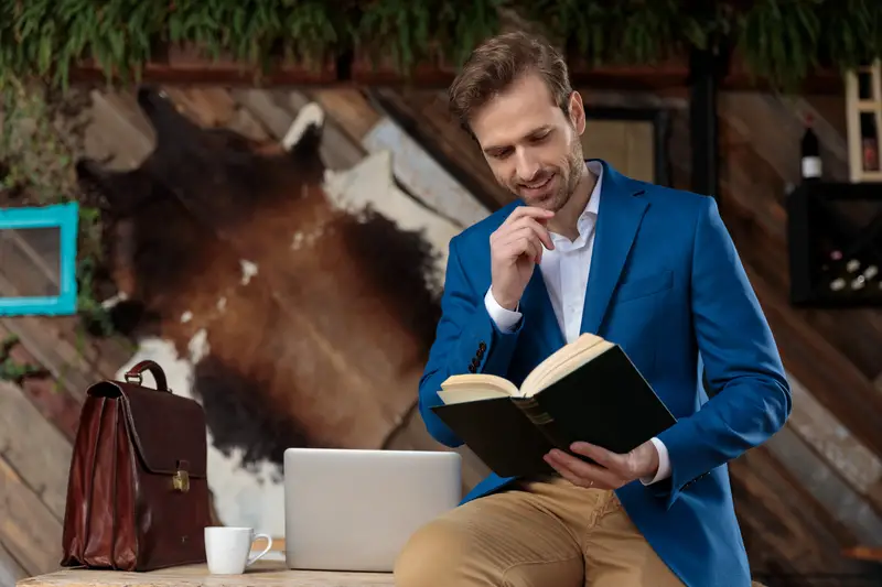 Businessman reading a book with his hand on his chin