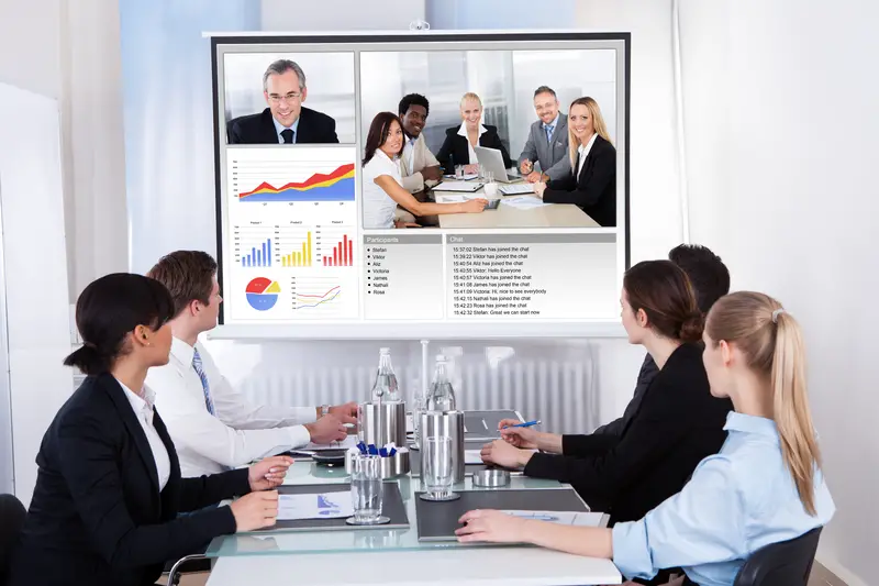 Businesspeople Sitting In A Conference Room Looking At Screen