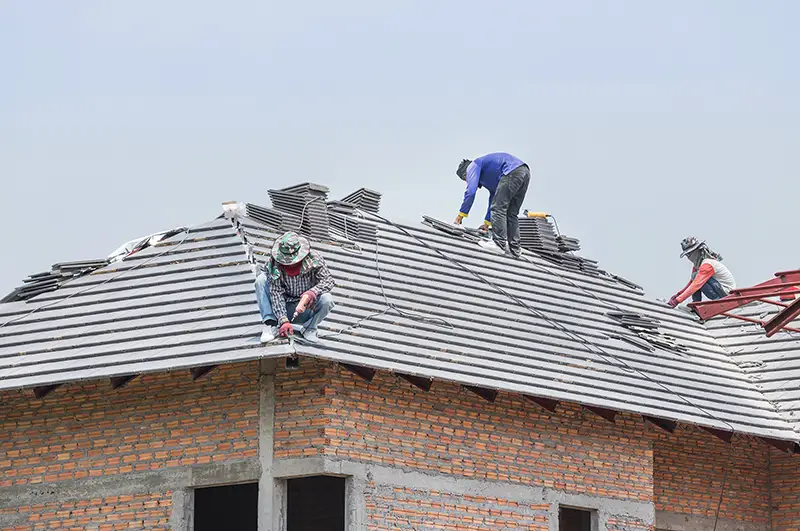 Workers installing concrete tiles on the roof