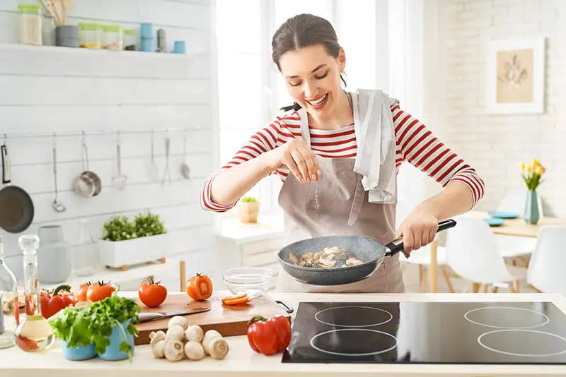 a girl poring seasonings on the pan while cooking