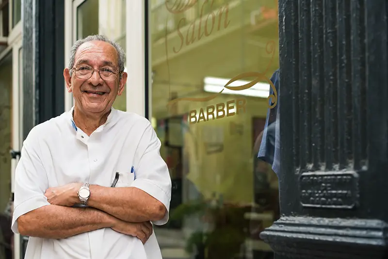 senior hispanic barber in old fashion barber's shop