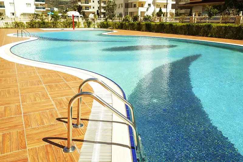 Swimming pool area of new luxury residential complex with tiles, chrome stairs handles and drains.