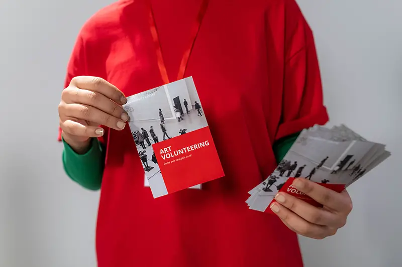phot of a woman in a red long sleeves holding a leaflet
