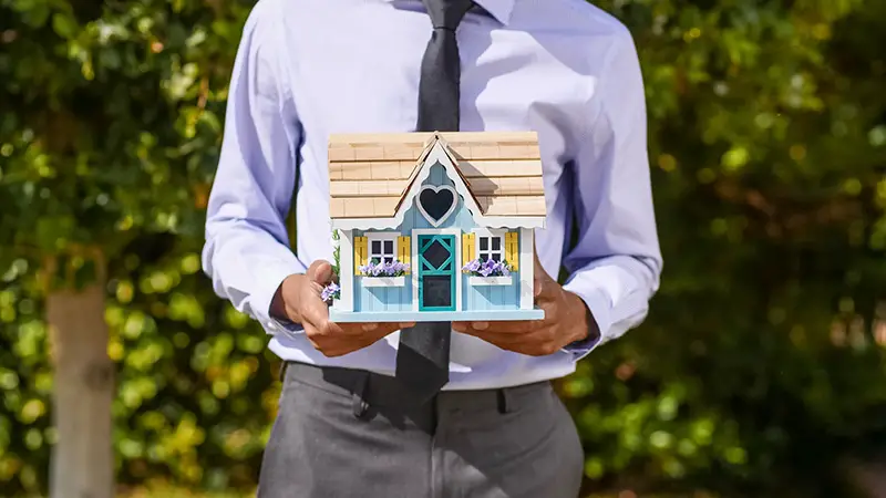 Person holding a miniature house