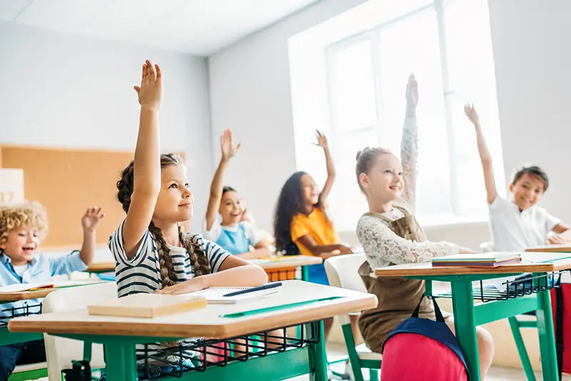 group of schoolchildren raising hands to answer question