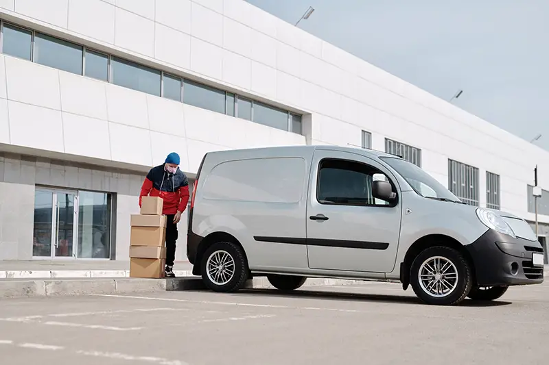 Delivery man with boxes next to white van