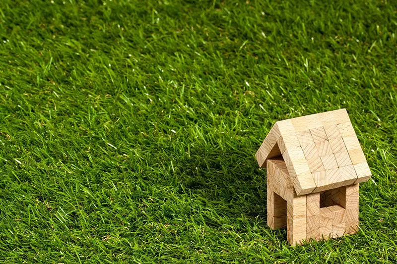 Wooden toy house on top of the green grass