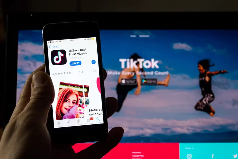 TikTok mobile video-sharing app company logo on phone screen with internet homepage in background