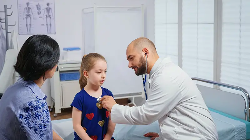 medical practitioner listening to girl heartbeat