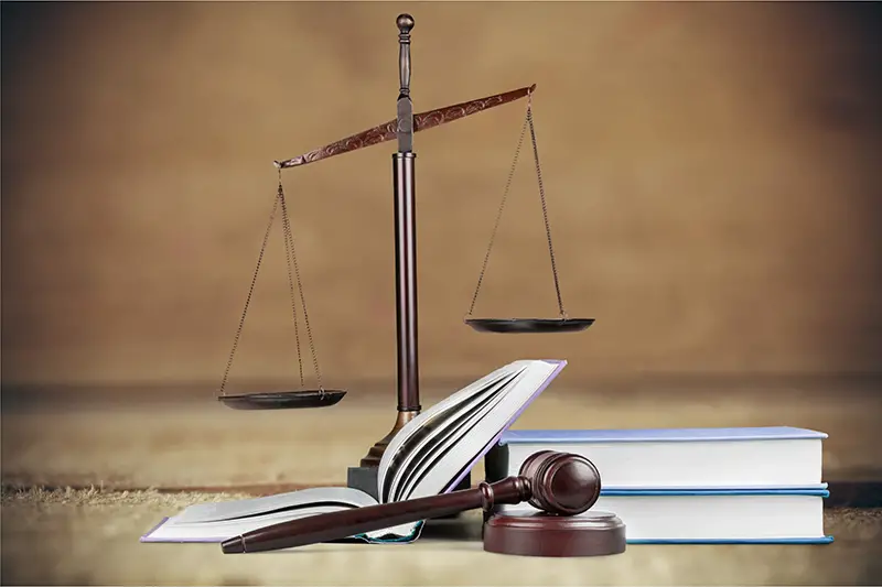 Judge gavel, old books and scales on a wooden table