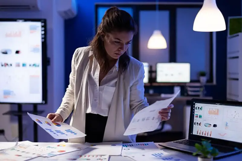 Woman in white coat looking at the graph printed in bond paper