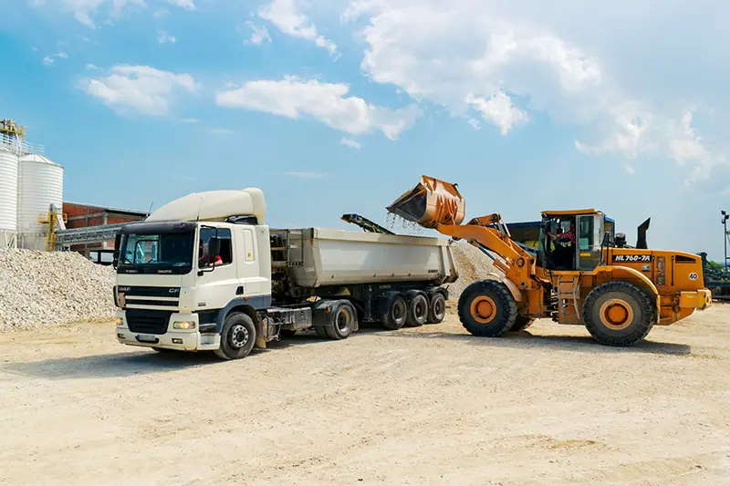 Brown loader beside white cargo truck