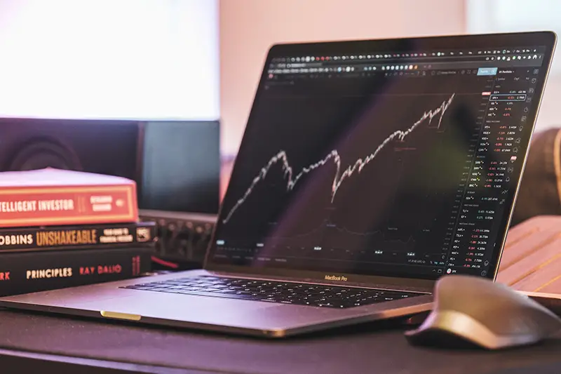 Black and silver laptop with trading graph on screen