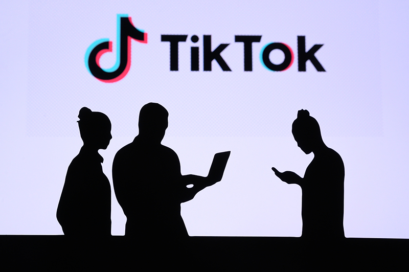 Tiktok logo and 3 shadow of people exchanging messages