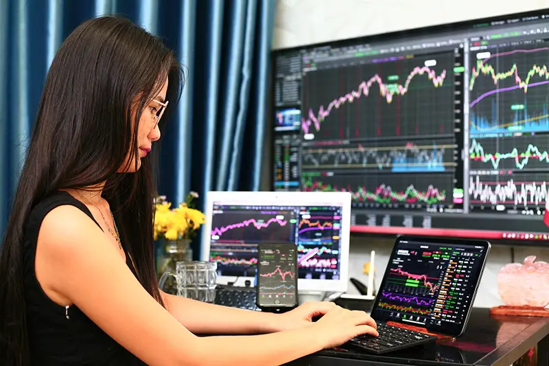 Woman in front of computer trading graph