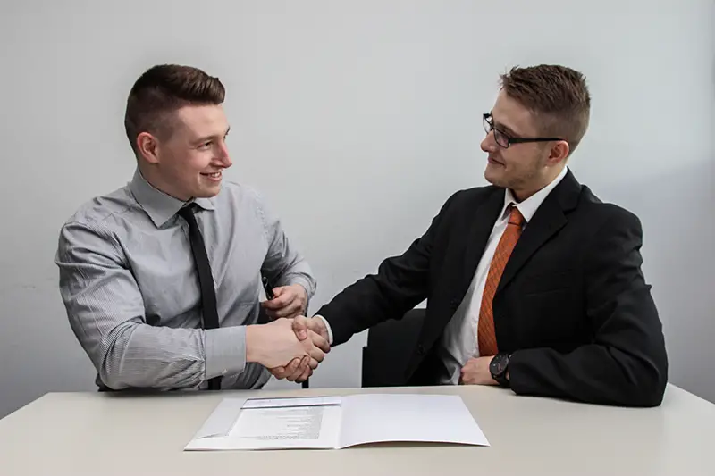 two men facing each other while shaking hands