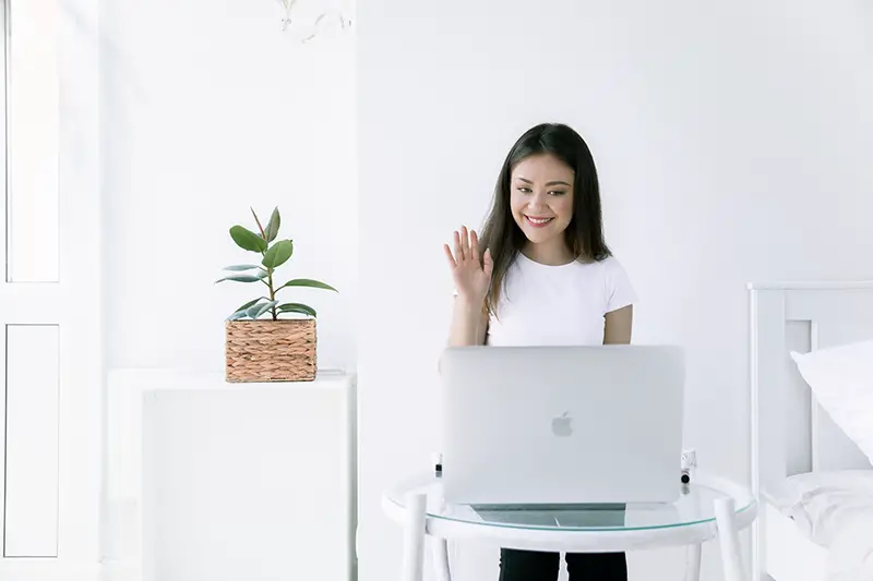 Woman waving in front of her laptop