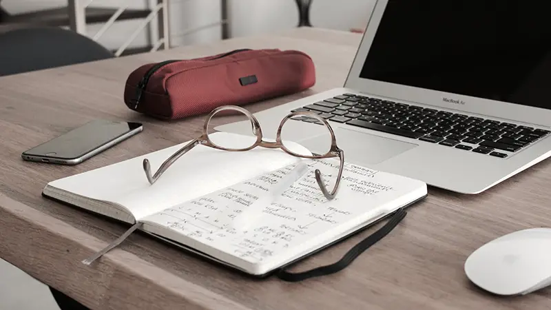 laptop and notebook placed on the wooden table