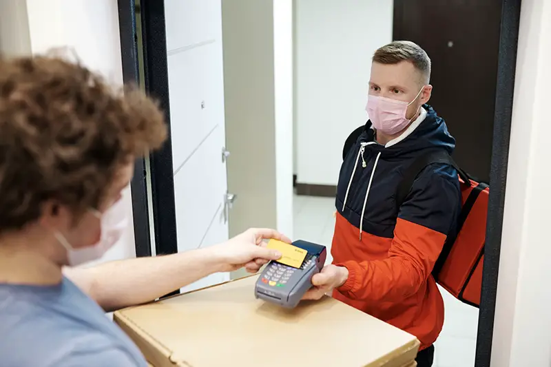 Person wearing facemask while paying the delivery