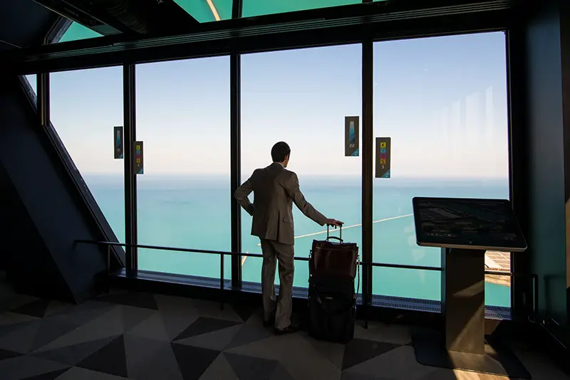 Man carrying luggage standing near glass window