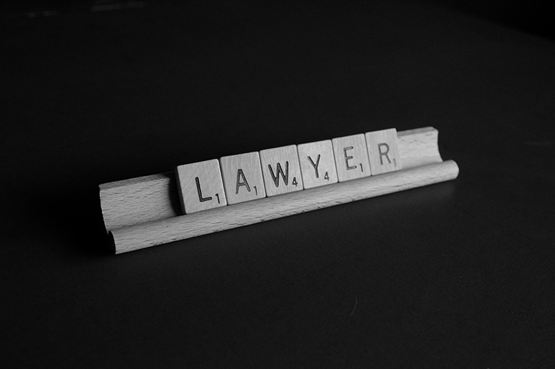 brown wooden scrabble on black background with word formed lawyer